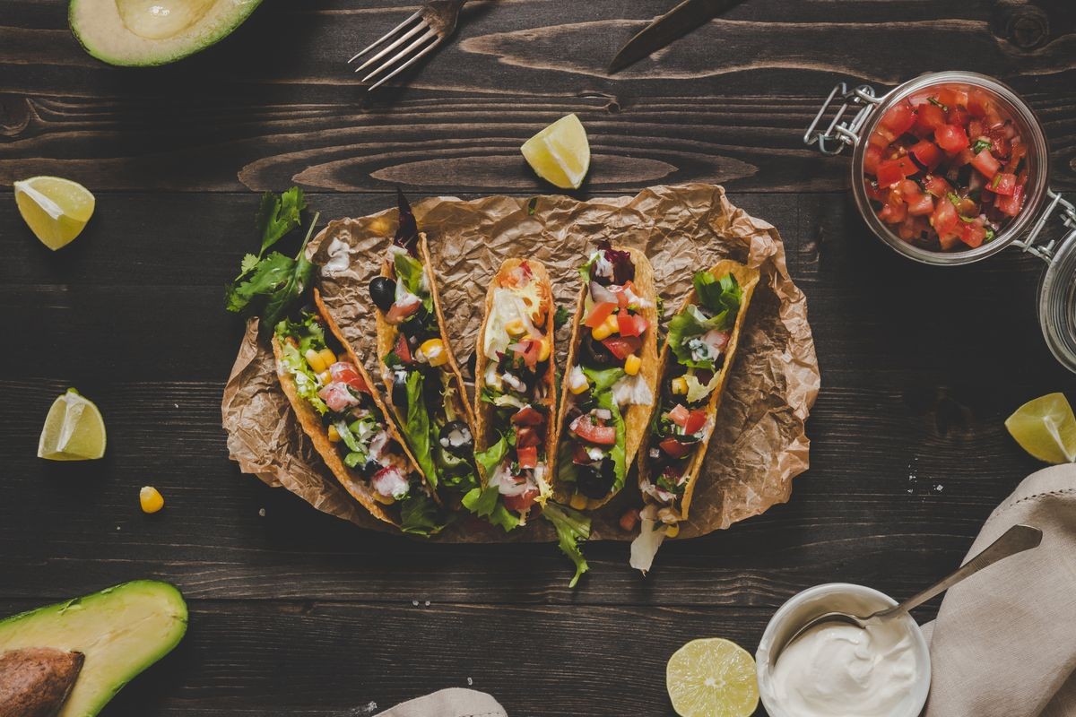 Mexican tacos with salsa and avocado on the wooden background, top view.
